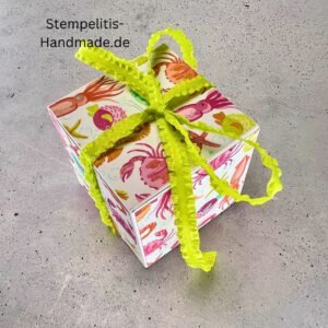 Handdekorierte Geschenkschachtel mit Schleife von oben, Geschenkschachtel mit liebevollem Aufkleber “Mit viel Liebe verschenkt”, Detailansicht Schleife auf Geschenkschachtel, Seitenansicht Geschenkschachtel mit buntem Designpapier, Offene Geschenkbox zum Befüllen, Geschenkschachtel auf hellem Hintergrund mit Dekorband, Handgemachte Geschenkverpackung mit grünem Band und Etikett